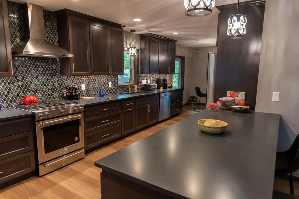 Wauwatosa kitchen remodeled by Reality Construction with dark cabinetry, a stainless range and a tiled backsplash